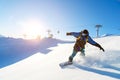 A snowboarder in a ski mask and a backpack is riding on a snow-covered slope leaving behind a snow powder against the Royalty Free Stock Photo