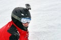 Snowboarder or skier portrait in sport goggles and protection helmet with mounted action camera and ski slope on background. Royalty Free Stock Photo