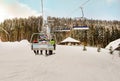 Snowboarder and skiers ride on a ski lift to a snowy mountain on a sunny day. Winter landscape