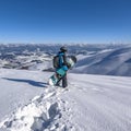 Snowboarder with snowboard in hand on mountain top. Winter freeride snowboarding