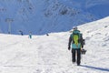 A snowboarder with a snowboard in his hand is walking along the slope of a ski resort. Snow-capped mountains on the background Royalty Free Stock Photo