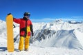 Snowboarder standing with board high in the mountains i