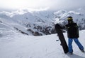 Snowboarder standing with his snowboard on slope