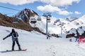 Snowboarder standing on snowy mountain slope in Sochi Krasnaya Polyana ski resort on a sunny day