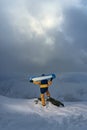 Snowboarder stands cliff and holding board on their shoulders