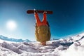 Snowboarder stands on head against mountains