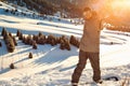 Snowboarder stands mountain top with his arms raised