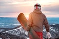 Snowboarder stands with snowboard against sunset Royalty Free Stock Photo