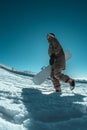 Snowboarder walking against blue sky