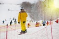 Snowboarder in yellow ski suit rises on lift up mountain slope. Ski sports in winter. Vacation in mountains in ski resort