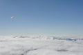 Snowboarders fly on a paraglider above the clouds
