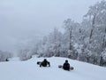 Snowboarders sitting on the trail looking down to beautiful panorama valley