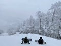 Snowboarders sitting on the trail looking down to beautiful panorama valley