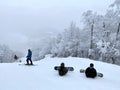 Snowboarders sitting on the trail looking down to beautiful panorama valley