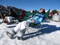 Snowboarders and skiers relax and sunbathe under the bright rays of the sun at the ski resort lying in sunbeds. Andorra, Andorra Royalty Free Stock Photo