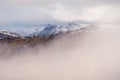 Snowcapped mountain range peaking out of low cloud. Lake District, UK.