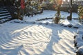 Snowcovered garden with sunlit patterns and trees Royalty Free Stock Photo