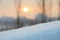 Snowdrift against sky and sun over buildings at sunset.