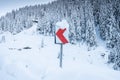 Snowed guide road sign of turn on a winter curved road through the mountains