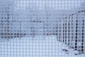 Snowed sport yard behind frosty metal grid net in winter