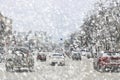 Snowfall and blizzard in city, cars on slippery road, poor visibility, dangerous situation on the road Royalty Free Stock Photo