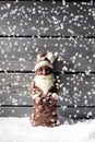 Snowfall with chocolate santa claus on heap of snow against wooden background Royalty Free Stock Photo