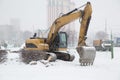 Snowfall in the city. Excavator with a large bucket.