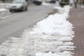 Snowfall in the city, the icy carriageway of the road and sidewalk, the concept of public utilities, seasonal changes in nature, Royalty Free Stock Photo