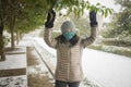 Snowfall in covid19 time - young happy and attractive Asian Japanese woman in winter hat and mask at beautiful city park playing Royalty Free Stock Photo