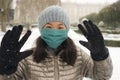 Snowfall in covid19 time - young happy and attractive Asian Korean woman in winter hat and mask at beautiful city park playing Royalty Free Stock Photo