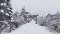 After the snowfall, there is snow on the road, trees and roofs of houses. Along the street there are mesh and wooden fences, a bus Royalty Free Stock Photo