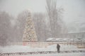 Snowfall in the winter. Snow blizzard in the city. Lantern, tree in the city, clearing the snow in the city