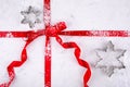 Snowflake cookie cutters on marble pastry board wrapped in red ribbon dusted with confectioners sugar