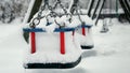 Snowflakes falling on empty swings at public playground and covering park with snow. Concept of winter holidays, bad weather and Royalty Free Stock Photo