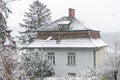 It is snowing against the background of an old country house. Concept: Snowfall and high precipitation in winter, the beginning of
