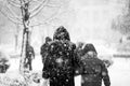 Snowing urban landscape with people passing by