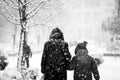 Snowing urban landscape with people passing by