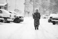 Snowing urban landscape with people passing by