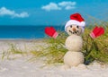 Snowman on the beach. Sandy Christmas snowman in red Santa hat and mittens or gloves. Royalty Free Stock Photo