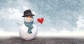 Snowman with black hat holding paper heart