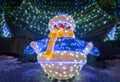 Snowman with bright lights and decorated fir.