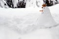 Snowman build in a garden covered with snow. It has nose made of carrot,  face of black buttons and a hat of dry leaves. Royalty Free Stock Photo