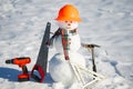 Snowman builder with construction tools. Winter snowman worker. Snow man engineer with hardhat. Funny snowman builder. Snowman Royalty Free Stock Photo