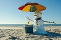 snowman with a cooler and drink, relaxing under a beach umbrella