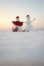Snowman couple with present box in basket. Royalty Free Stock Photo