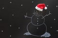 Snowman drawn with chalk on blackboard with Santa Claus hat, creative concept christmas background