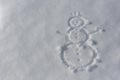 A snowman drawn with a finger on a white fluffy surface of snow. Top view. Flat lay. Text space on the left.