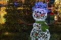 Snowman with garlands at night. Traditional Christmas market decorations in the city. New Year celebration, holidays Royalty Free Stock Photo