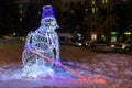 Snowman hockey player with a hockey stick in the form of a light Christmas installation.