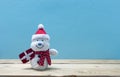 snowman holding a Christmas present on wood , blue wall background. Royalty Free Stock Photo